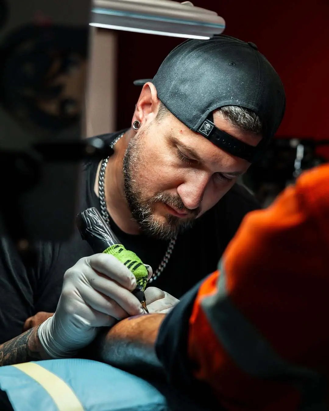 Close portrait of a tattooist mid session, machine in hand, concentrating on the work