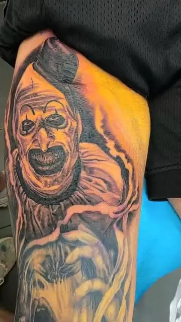 A colour horror film character portrait on a thigh, lit in orange against heavy black shadow